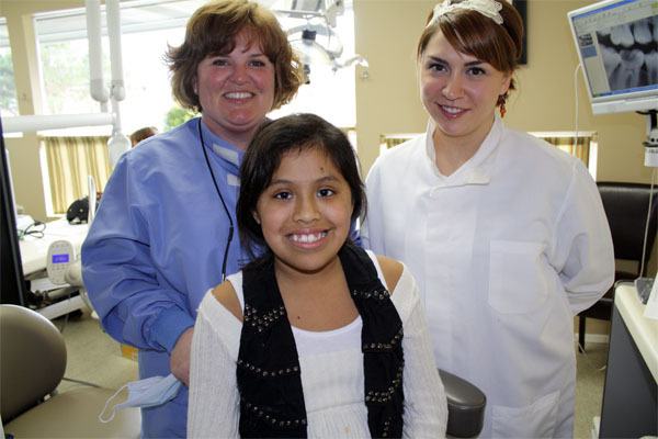 Dentist Kelly Garwood and assistant Tara Crandall help patient Abigail during her Give Kids a Smile visit in March. Needy children receive free dental care and advice. Giving kids a smile: North Bend dental offices provide free care for needy youth.