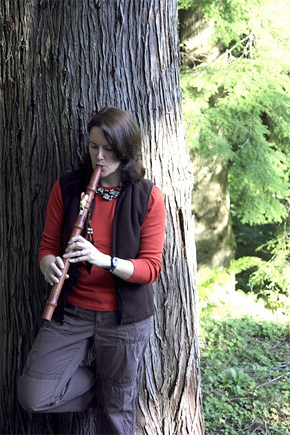 Carol Whitaker of Fall City plays a native flute in her backyard woodland. Whitaker welcomes visitors and players of all skill levels to the Native American Flute Circle