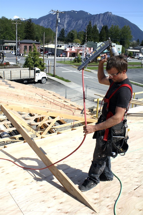 Michael McClellan installs a roof timber atop the new Snoqualmie Valley Clinic. Contractors are pushing to reopen the building by October