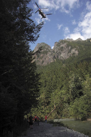 A Chinook aircraft flown by a pilot from Columbia Helicopters lifts a log from the Middle Fork of the Snoqualmie River