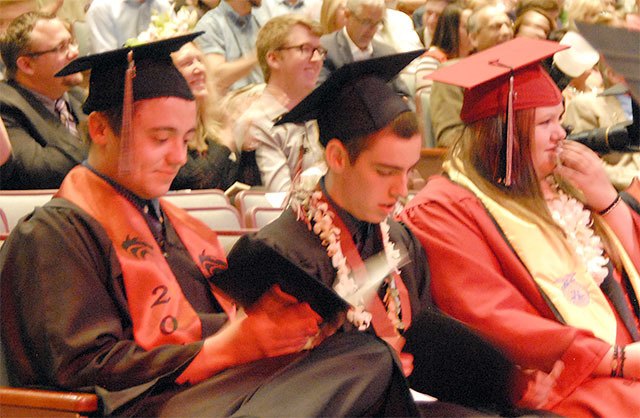 Cedarcrest High School seniors examine their new diplomas with various emotions.