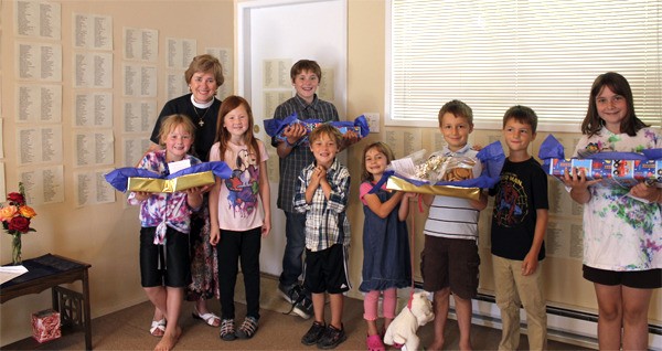 Young congregation members and St. Clare priest Patty Baker share goodies with local police and firefighters on Sept. 11. The wall behind them shows the names of victims of the 2001 attacks.