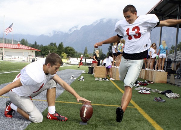 Senior Chase Carlson holds the ball for junior Cameron Van Winkle during practice. Van Winkle