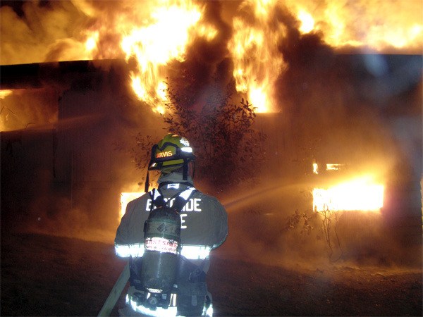 An EF&R firefighter works to control a home fire in rural Preston Thursday morning. The home was a total loss