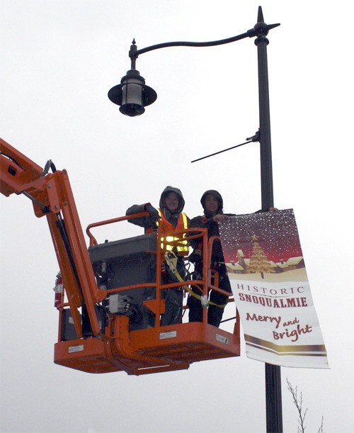 City staff hang Christmas decorations last week in downtown Snoqualmie. An official holiday celebration is Saturday