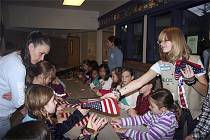 Taylor Wiles passes out mini-flags to teach girls from Troops 3442