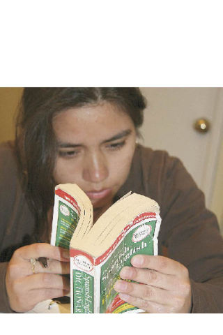 Liliana Reyes searches for a word in her English-Spanish dictionary during a writing exercise at a class at St. Clare Episcopal Church. A native of El Salvador