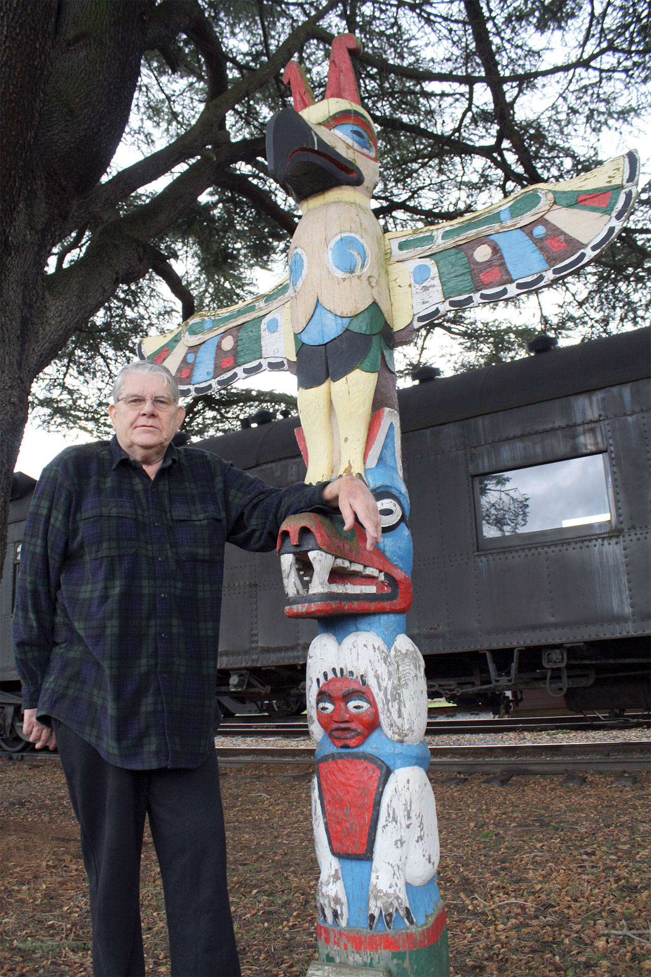 Snoqualmie councilman Charles Peterson visited the downtown Snoqualmie totem pole in this 2012 photo. The pole was removed during downtown construction and Peterson was adamant that it be reinstalled once the pole’s colors were restored. “It was going to happen if he had anything to say about it!” said Carol Peterson.                                File Photo