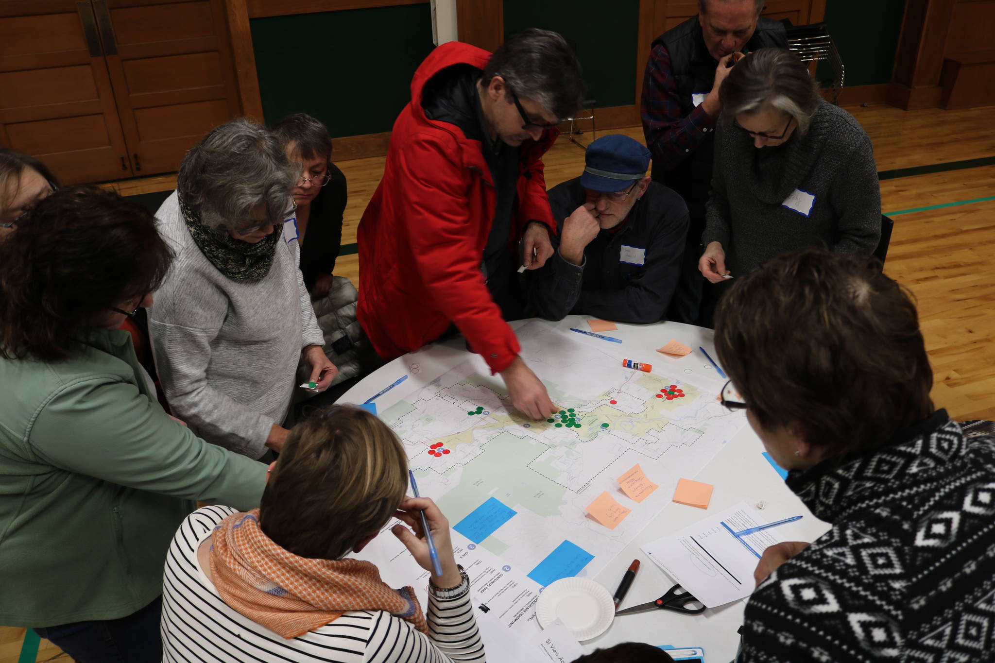 Photo by Evan Pappas/Staff Photo                                Community members gather around a map to discuss their opinions on where the future aquatics center should be located during the February public meeting.