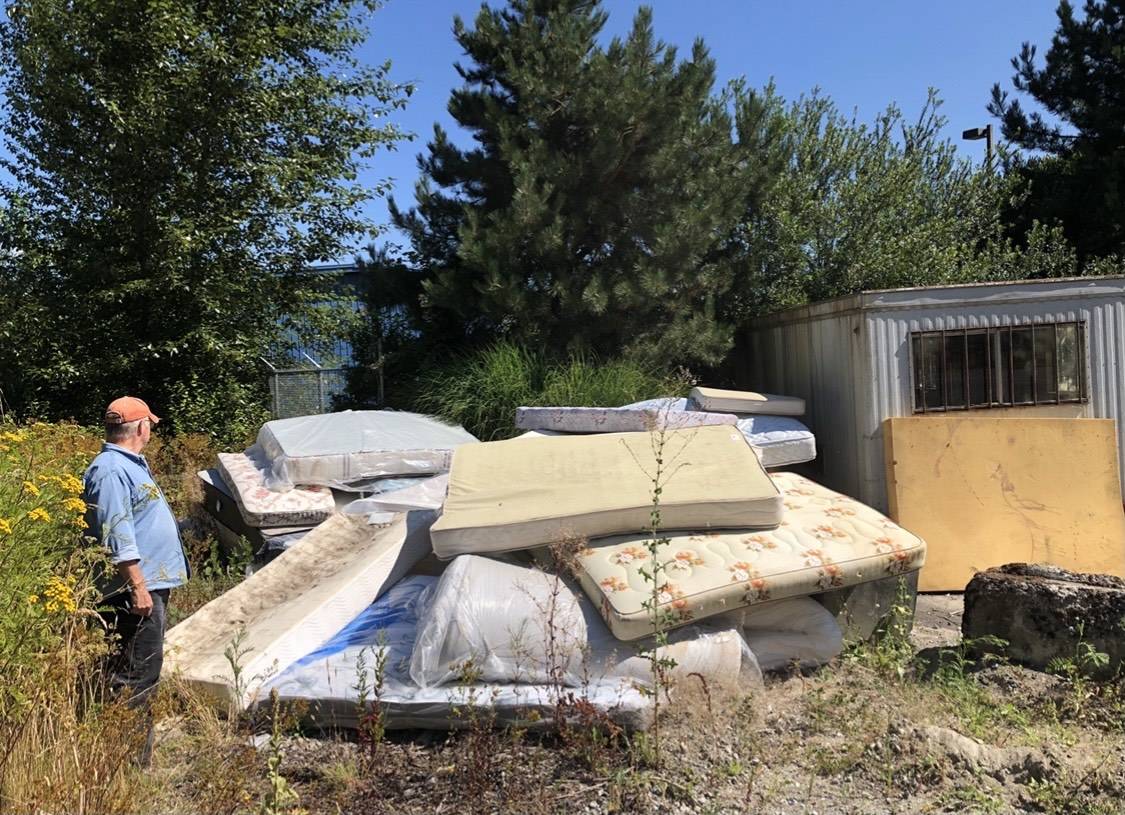 A man looks over a pile of mattresses which will be cleaned up and hauled away by Friends of the Trail. 	Contributed by Wade Holden