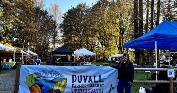 Duvall Farmers Market Board president Alex Yearout stands with the market’s new banner on Oct. 3, 2024. (Grace Gorenflo/Valley Record)