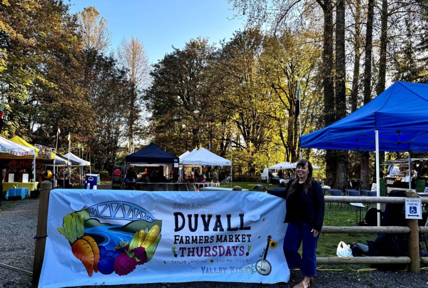 <p>Duvall Farmers Market Board president Alex Yearout stands with the market’s new banner on Oct. 3, 2024. (Grace Gorenflo/Valley Record)</p>