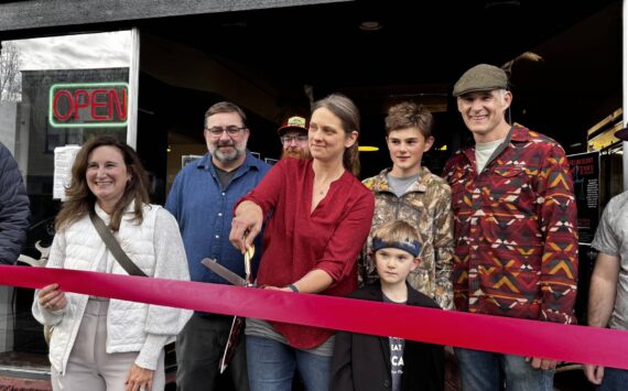 Christeena Marzolf prepares to cut a celebratory ribbon with family and friends at Falling River Meats Oct. 17, 2024. From left: Valerie Pacheco, Snoqualmie Valley Chamber of Commerce board secretary; Justin Fitch, Falling River Meats chef; Christeena Marzolf, Falling River Meats co-owner; Marcus Marzolf; Rowan Marzolf; Darron Marzolf, Falling River Meats co-owner. (Photo by Grace Gorenflo/Valley Record)