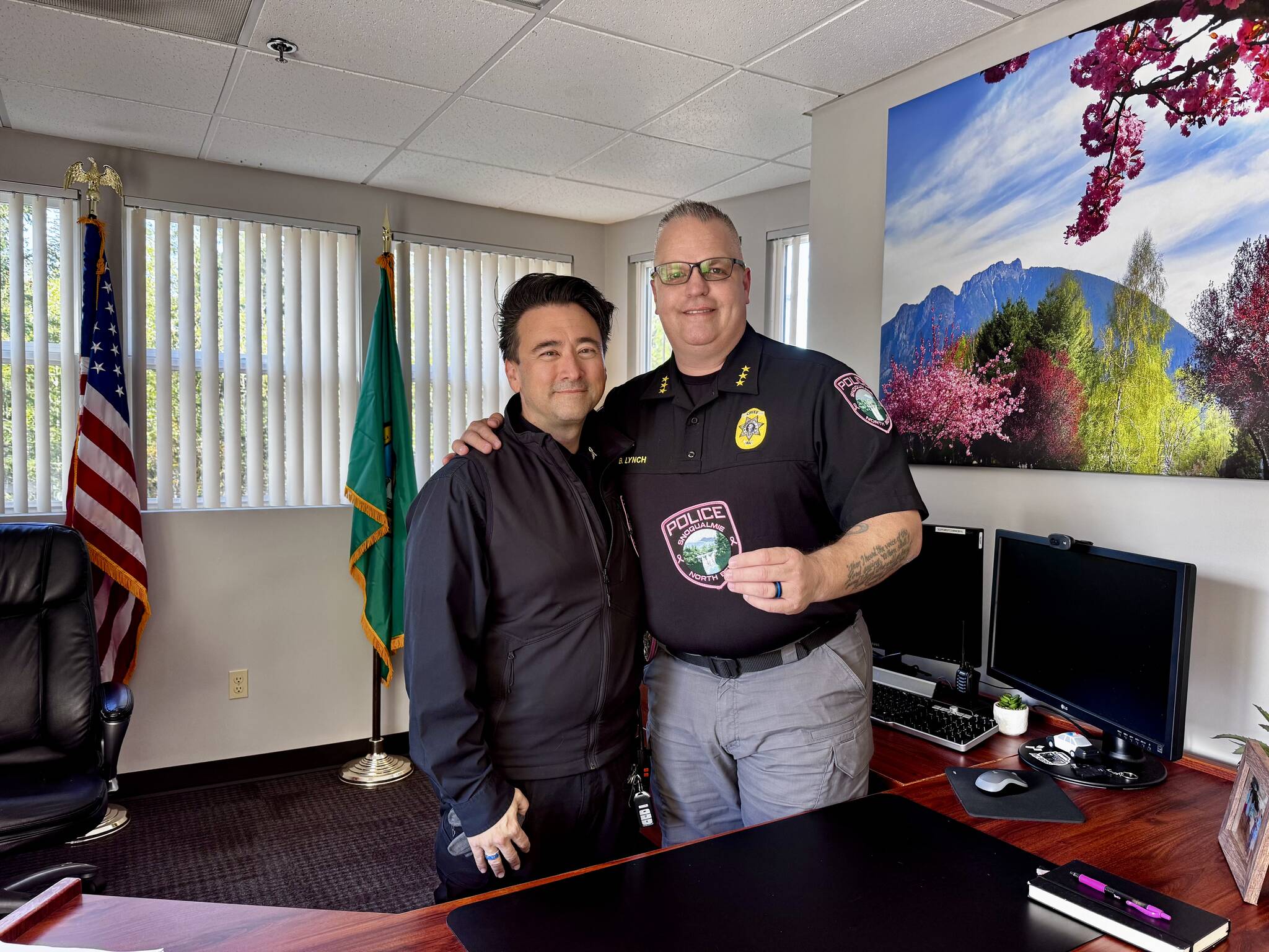 Snoqualmie Police Chief Brian Lynch (right) stands for a photo with evidence technician L.T. Liebetrau and the department's new breast cancer awareness patches. (Grace Gorenflo/Valley Record)