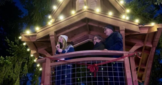 Aroma Coffee Co. co-owner Emily Ridout, joined by Pete and Judy Nelson, speaks to the crowd at the grand opening of Pete’s Treefort Dec. 7, 2024. (Grace Gorenflo/Valley Record)